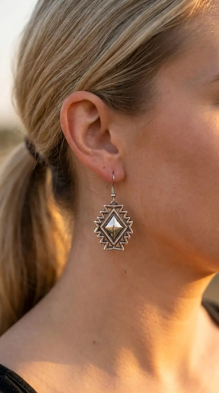 Close-up wearing the Cowhide & Conchos Southwestern concho earrings — Aztec-stamped silver detail up close.