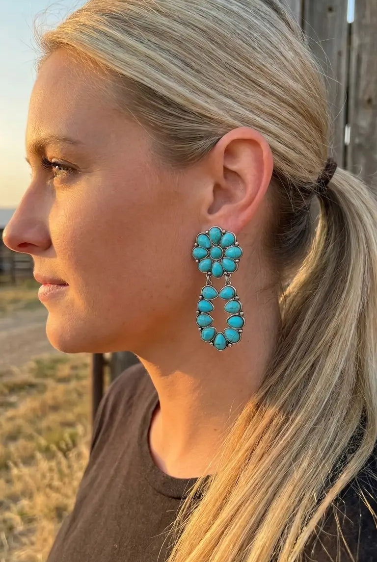 Close-up wearing the Cowhide & Conchos turquoise cluster earrings — vivid turquoise western detail.