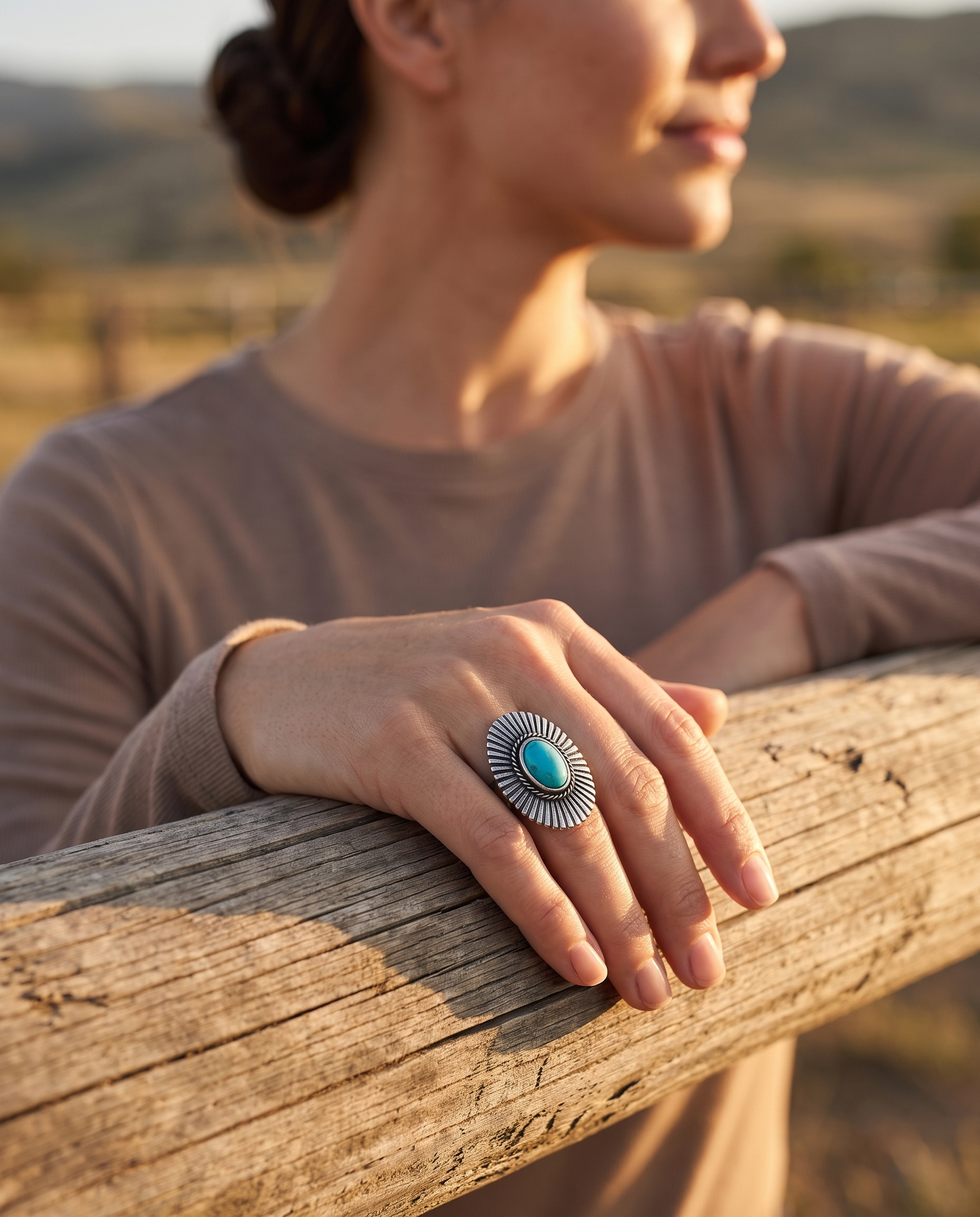 A hand on a ranch fence rail wearing the Cowhide & Conchos Western concho and faux-turquoise adjustable statement ring — bold western style.