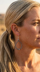 Close-up wearing the Cowhide & Conchos desert pearl saucer earrings — antiqued silver western detail.