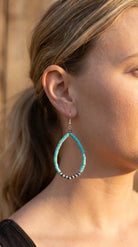 Close-up wearing the Cowhide & Conchos turquoise teardrop earrings — beaded western detail up close.