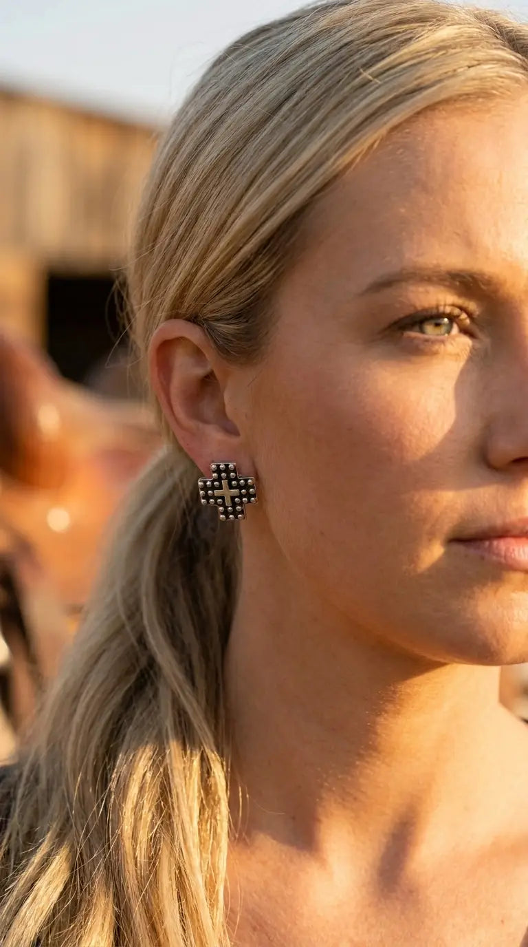 Close-up wearing the Cowhide & Conchos cross stud earrings — studded silver detail up close.