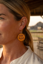 Ranch woman in golden-hour profile wearing the Cowhide & Conchos Made to Rodeo bottle-cap earrings — rodeo-ready western style.