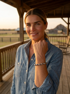 Blonde ranch model at golden hour wearing the Cowhide & Conchos 3mm & 6mm Sterling Pearl Bracelet — delicate everyday sterling, effortless Western style.