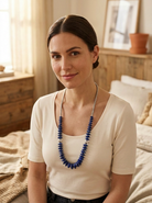 Brunette model in a warm western bedroom wearing the Cowhide & Conchos Graduated Lapis Necklace — rich blue lapis and sterling pearl, bold Western color.