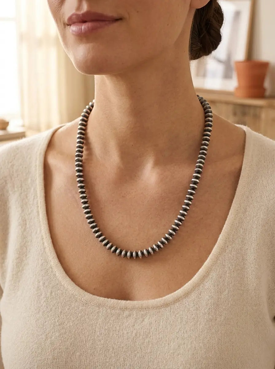 Close-up of the Bryannen Halwood Navajo Saucer Pearl Necklace — flat hand-finished sterling silver saucer beads in soft golden light.