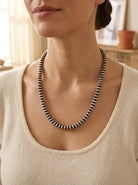 Close-up of the Bryannen Halwood Navajo Saucer Pearl Necklace — flat hand-finished sterling silver saucer beads in soft golden light.