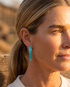 Handcrafted by Zuni silversmith Terrance Panteah — sterling silver tapered turquoise earrings, TP hallmark, worn at golden hour.